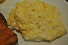 a white plate topped with meat and mashed potatoes next to a slice of bread