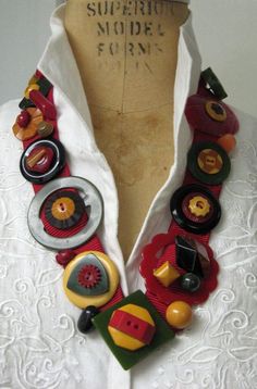 a white shirt with buttons on it and an orange, red, yellow and green necklace