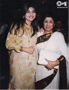 two women standing next to each other in front of a crowd at an event, one holding a white purse