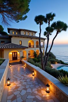 a house with some lights in front of it and the ocean behind it at night