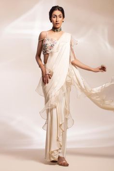 Off-white stitched drape saree with organza ruffled drape. Comes with padded blouse with pearl straps embellished with beads, pearl, and sequin in hues off-white, light blue, pink, peach and tones of grey highlighted with gold and silver beading.
Components: 2
Pattern: Embellished
Type Of Work: Beads, Sequins, Pearls
Neckline: Sweetheart
Sleeve Type: Sleeveless
Fabric: Saree: Modal satin , Ruffles: Organza, Blouse: Tulle 
Color: Off White
Other Details: 
Attached lining
Approx. product weight: 2 Pearl Straps, Off White Saree, Organza Blouse, Ruffle Saree, Padded Blouse, White Saree, Drape Saree, Embellished Blouse, Blouse For Women