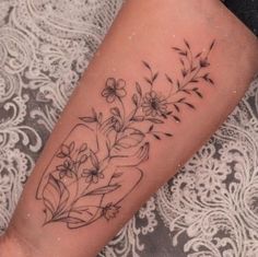 a woman's arm with flowers and leaves on it