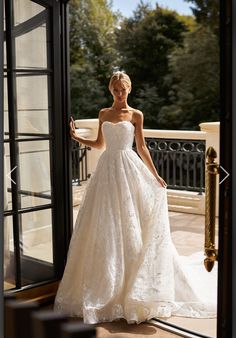 a woman in a wedding dress is standing by an open door