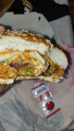 a hand holding a sandwich with meat, cheese and other toppings on the bun