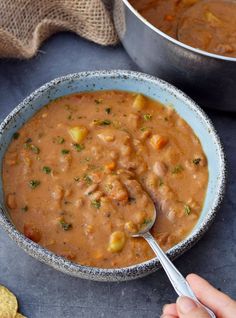 two bowls filled with soup on top of a table next to crackers and bread