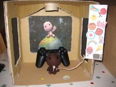 a stuffed animal is sitting in a cardboard box with a video game controller attached to it