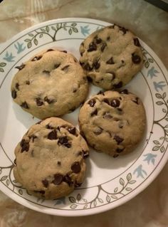 four chocolate chip cookies on a white and blue plate