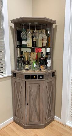 a corner bar with wine glasses and liquor bottles on the top, in front of a window