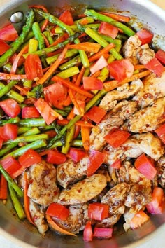 a pan filled with chicken, asparagus and tomatoes