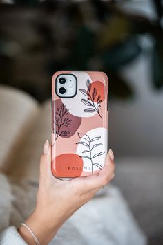 a woman holding up her phone case that has flowers on the back and leaves on the front