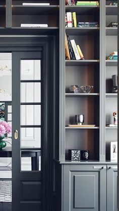 an open bookcase with many books and vases on it in front of a door