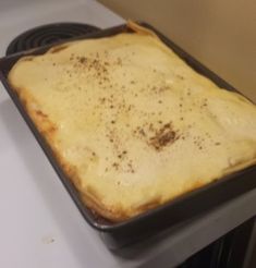 an uncooked pizza sitting on top of a stove in a pan with sauce and seasoning