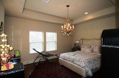 a bed room with a neatly made bed and a chandelier hanging from the ceiling