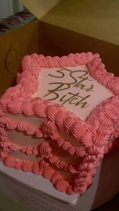 a pink birthday cake with white frosting and writing on the side in a box