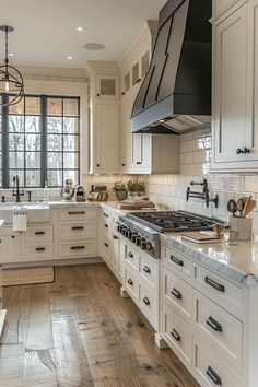 a large kitchen with white cabinets and wood floors is pictured in this image, there are two ovens on each side of the stove