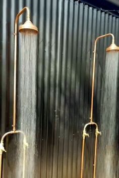 three water faucets are shown in front of a corrugated wall with metal slats