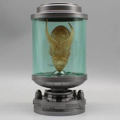 a glass jar with a skull in it on top of a metal stand and base