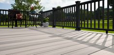 a wooden deck with black iron railing and chair