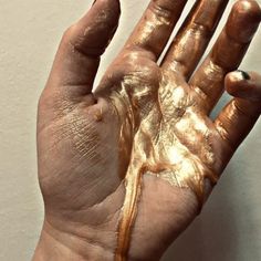 a person's hand with gold paint on it and the palm of their hand