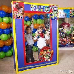 two children standing in front of an action figure photo frame with balloons and streamers