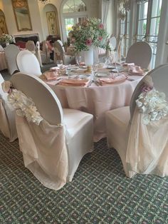 a dining room set up for a formal function with white chairs and pink sashes