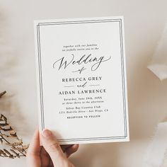 a person holding up a wedding card with the wording in black and white on it