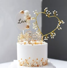 a white cake with gold decorations and a love sign on top that says, love