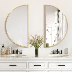 a bathroom with two round mirrors above the sinks and a vase full of flowers on the counter