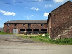 an old brick building sitting on the side of a road next to a green field