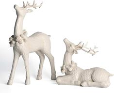 two white deer figurines sitting next to each other on a white table top