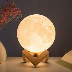 the moon lamp is next to two vases with flowers in them on a table