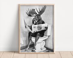 a black and white photo of a moose sitting on top of a toilet reading a newspaper