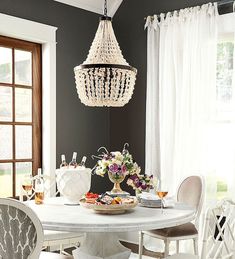 a dining room table with white chairs and a chandelier hanging from the ceiling