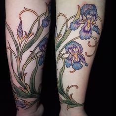 two tattoos on both legs with blue and purple flowers in the middle one has green leaves