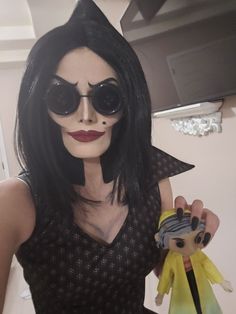 a woman in black and white makeup holding a doll