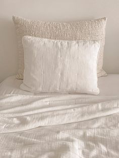 a white bed with two pillows on top of it