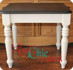 a small white table with black top and legs on wooden floor next to dressers