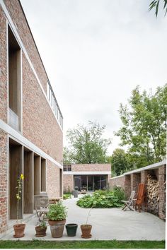 an outdoor courtyard with potted plants and chairs on the ground, surrounded by brick buildings