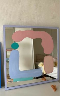 a mirror that is sitting on top of a table next to a blue box with an object in it