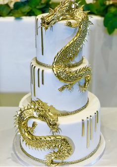 a three tiered white cake with gold dragon decorations