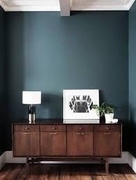 a living room with blue walls and wooden furniture in the corner, along with two lamps on either side of the table