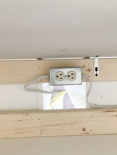 an electrical outlet with two plugs attached to the side of a wooden beam in a room