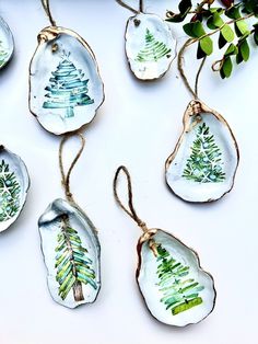 four ceramic ornaments with trees on them hanging from twine