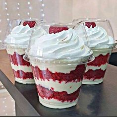 red velvet desserts in plastic cups with white frosting and strawberries on top