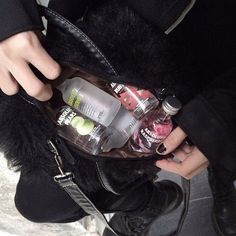 a woman is holding a purse full of bottles