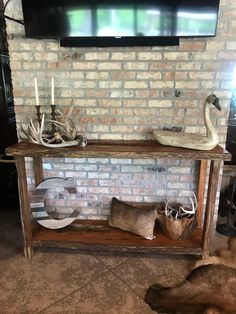 a tv mounted to a brick wall next to a wooden shelf with antlers on it