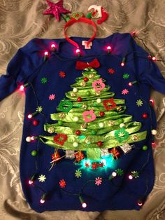 a blue sweater with a green christmas tree on it and lights around the neckline