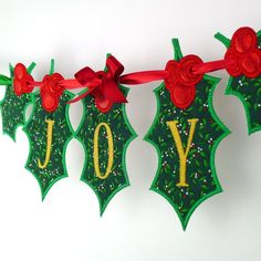 an embroidered banner with the word joy hanging from it's sides and decorated with red ribbon