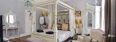 a white canopy bed sitting inside of a bedroom