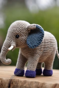 an elephant made out of yarn sitting on top of a piece of wood